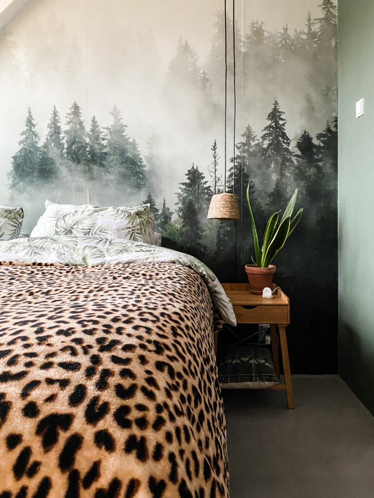 slaapkamer met mistig bos fotobehang, tijgerprint plaid op de zwarte boxspring