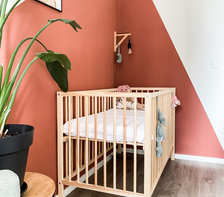 houten ledikant met terracotta accentmuur in de stoere babykamer