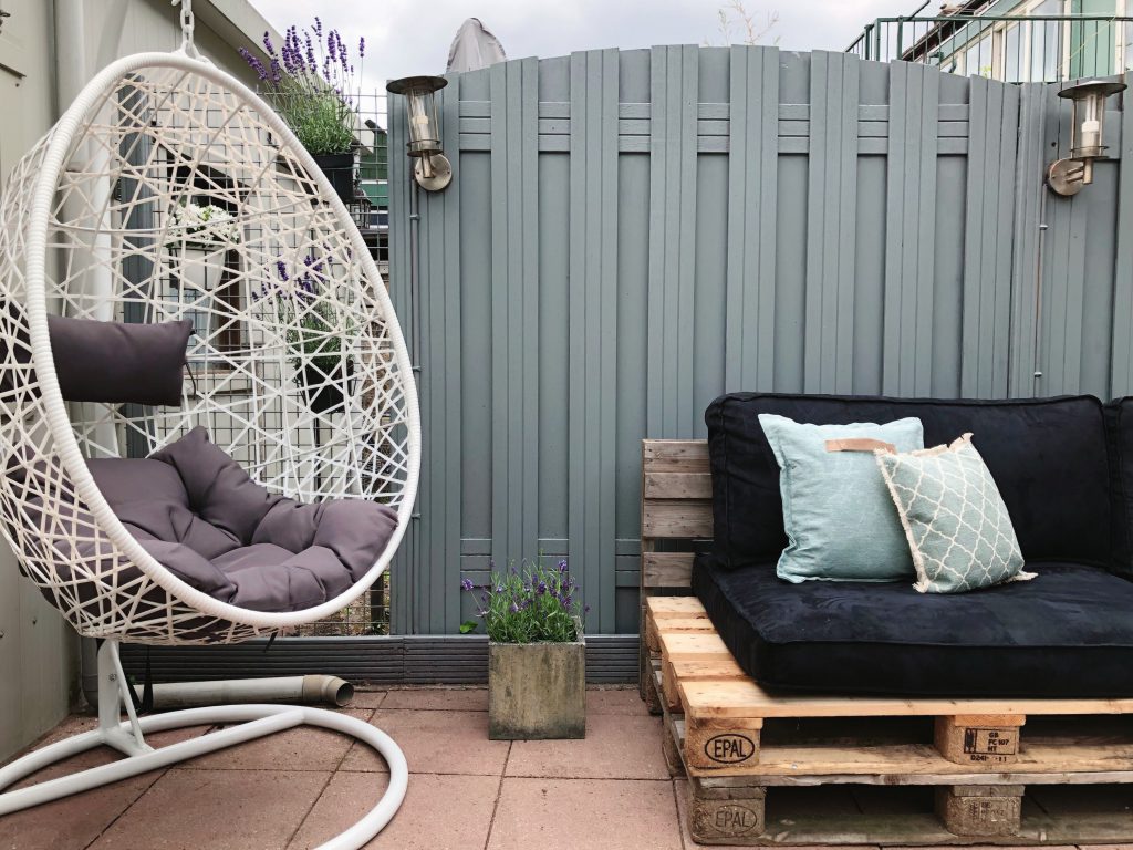 tuin make-over resultaat: hangstoel ei met daarnaast een pallet bank met zwarte kussens erop